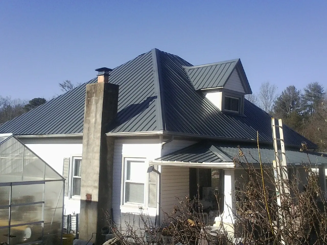 Dark blue standing seam metal roof on a white farmhouse with dormer — Slate & Tile Roof Repair by Roofing Brothers in Smithsburg