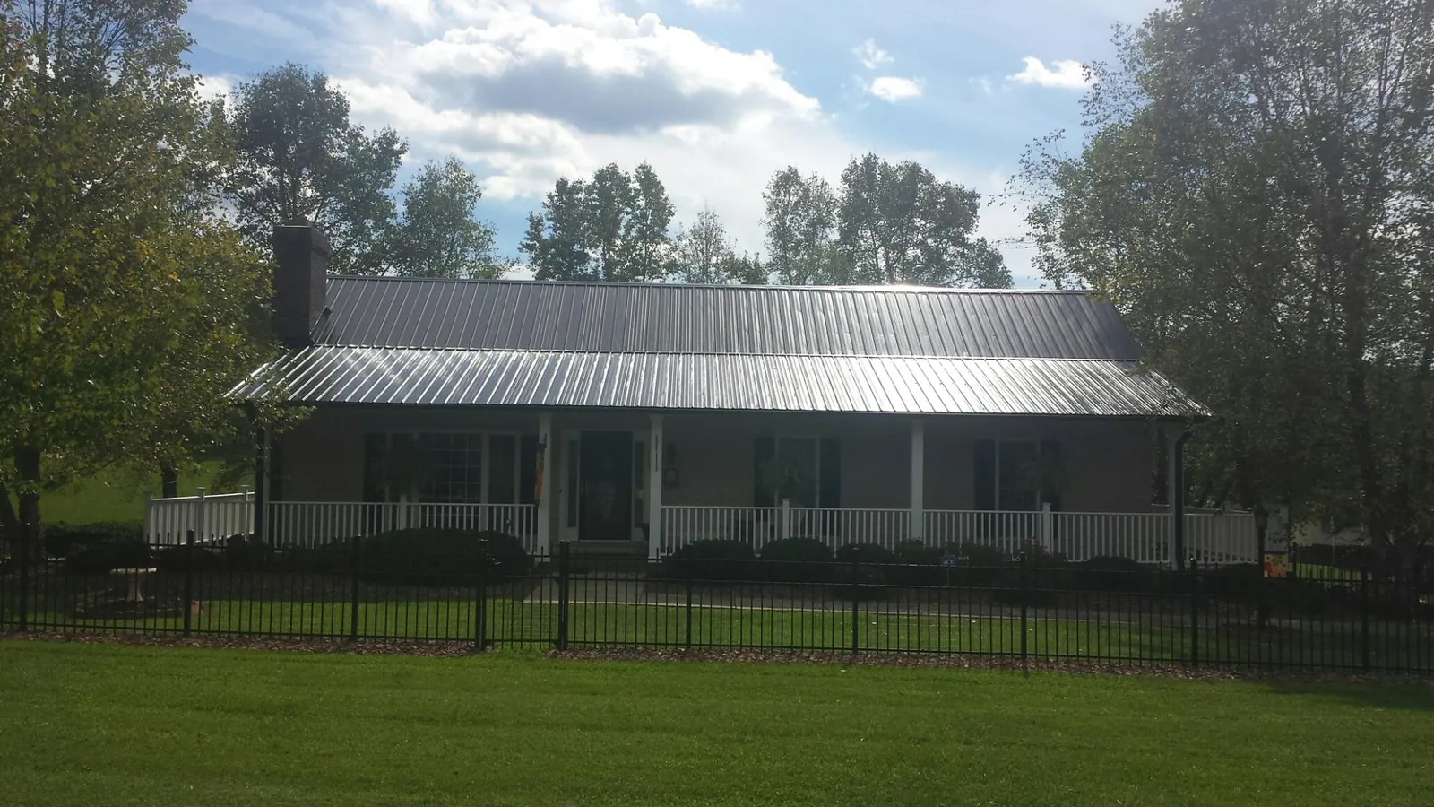 Gray metal roof on a brick ranch with a full width front porch — Gutter Guard Installation work by our crew in Smithsburg