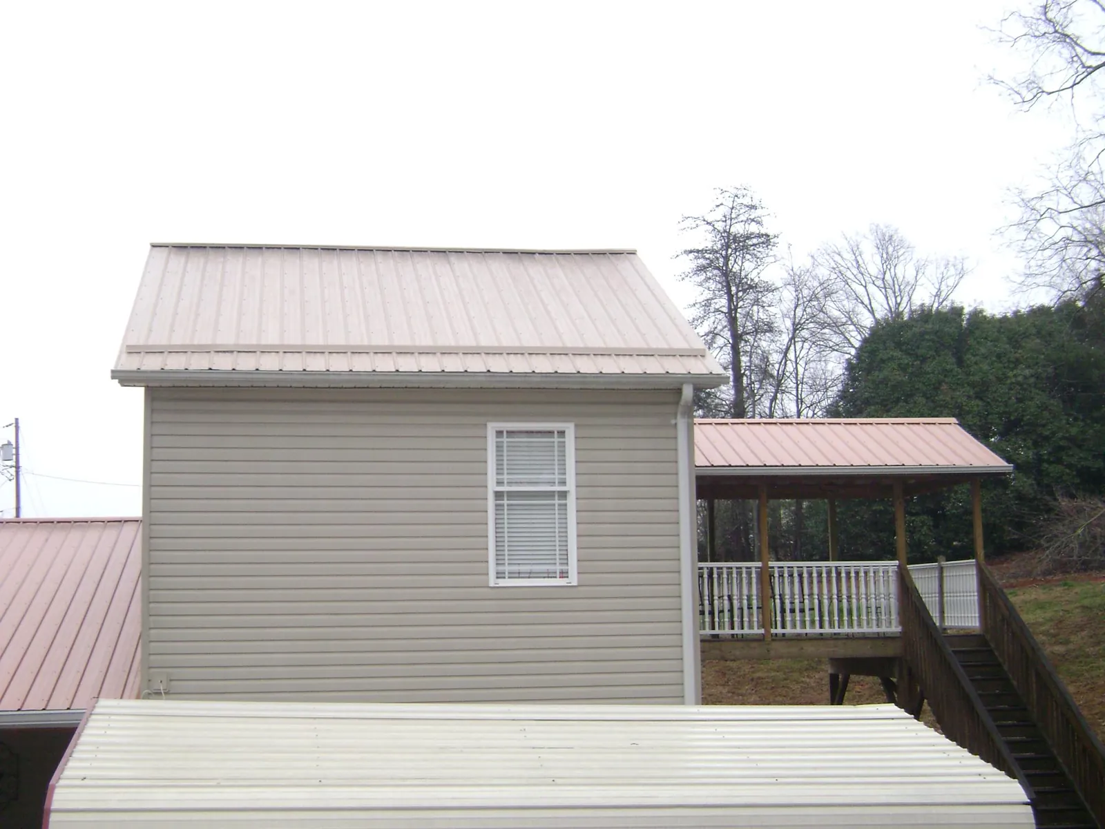 Tan metal roofs on a two story addition and attached porch, from a Roof Replacement job in Smithsburg