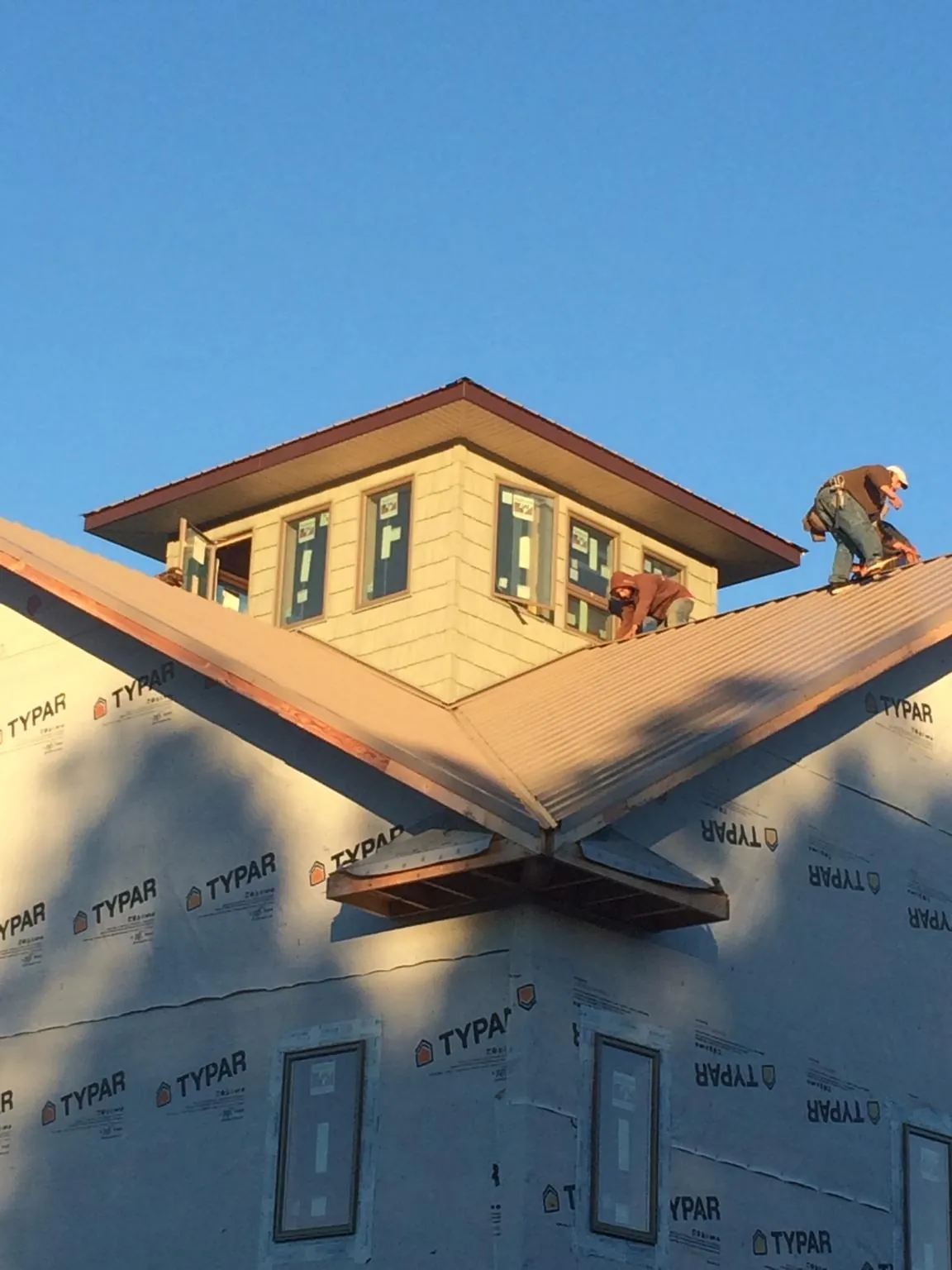 Roofers working around a rooftop cupola on a new metal roof at sunset — Roof Waterproofing in Smithsburg by Roofing Brothers